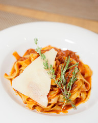 Pasta with tomato sauce, slice of parmesan, thyme and rosemary