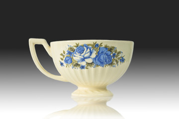 Flowered antique tea cup isolated on a reflection background.
