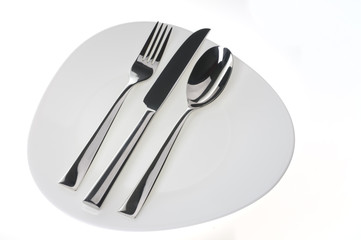 Fork, spoon and  knife on a plate over white