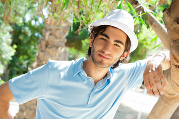 Young man wearing hat and casual clothes in sunny day. Leaning o