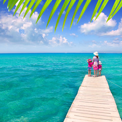Fototapeta premium Daughters and mother in jetty on tropical beach