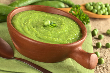 Fresh green pea soup in rustic bowl