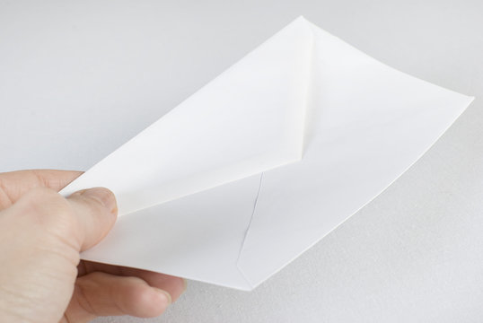 Female hand holding an envelope over white background. Not isola