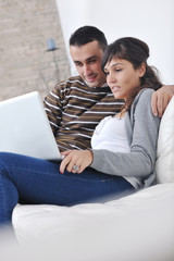 Fototapeta premium joyful couple relax and work on laptop computer at modern home