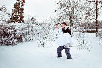 groom carries his bride in winter