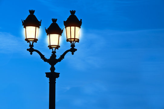R&eacute;verb&egrave;re allum&eacute; &agrave; Paris la nuit, lampadaire parisien classique sur fond de ciel bleu avec de l'espace