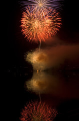 Colorful fireworks on black sky background with water reflection