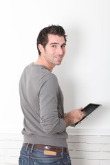 Man leaning on wall with electronic tablet