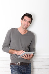 Man leaning on wall with electronic tablet