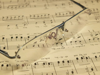 Pair of glasses laying on stave for folksong