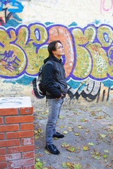 Young man in front of graffiti wall
