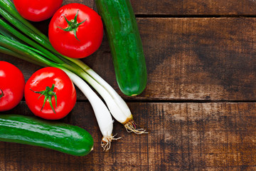Tomatoes, cucumber and spring onions on old wooden table