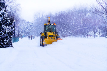Snow plow clears the road during winter storm.