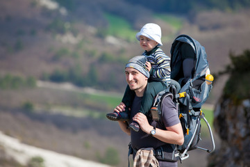 Father is hiking with the 1.5 year baby in baby carrier