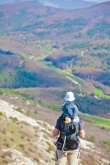 Father is hiking with the 1.5 year baby in baby carrier