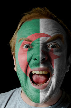 Face of crazy angry man painted in colors of algeria flag