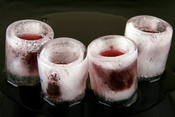 Ледяные стаканы с красным напитком на чёрном фоне