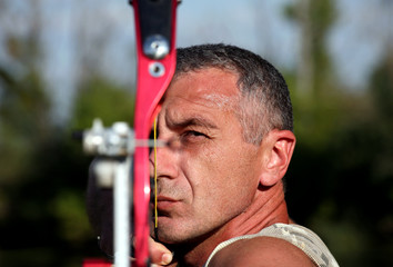 Portrait of professional bowman aiming with bow and arrow