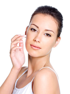 Young woman applying cosmetic cream on face
