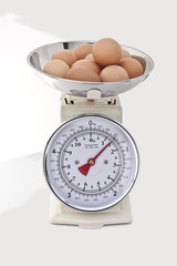 Kitchen Scales with fresh eggs on white background