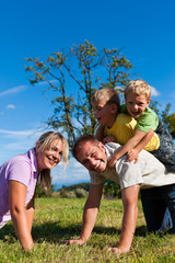 Familie mit Kindern spielt auf einer Wiese