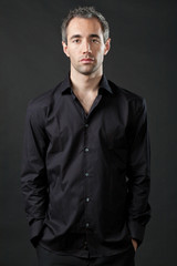 Obraz premium Handsome man posing in black shirt on dark background.