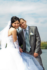 Happy bride and groom against blue sky