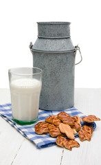 Бидон, печенье и стакан молока на деревянном столе