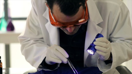A CSI agent using a UV light to examine evidence.