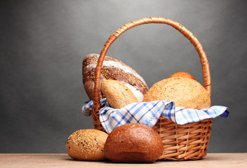 delicious bread in basket on wooden table on gray background