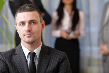 Handsome executive businessman with his team working behind