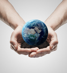 A handful soil with the Earth in the male hands