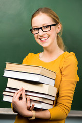Female student at chalkboard with books
