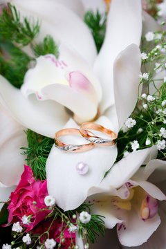 Wedding gold rings lie on a bunch of flowers for the bride