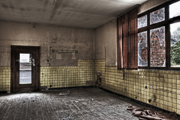 Empty room with broken window and yellow tiled wall in an abando