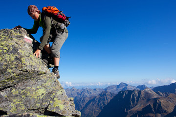 Young man climbing the mountain ridge