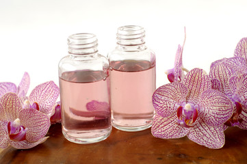 pink orchid and massage oil on wooden board