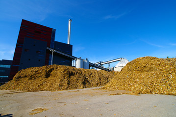 bio power plant with storage of wooden fuel against blue sky