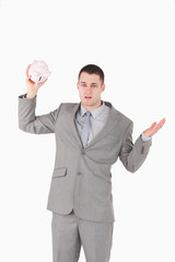 Portrait of a broke businessman shaking an empty piggy bank