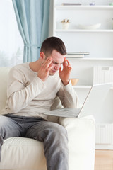 Fototapeta premium Portrait of a man having a headache while using a laptop
