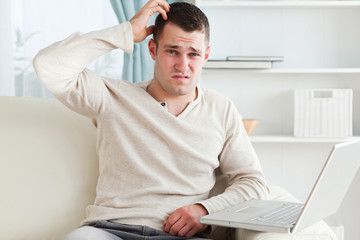 Confused man using a laptop