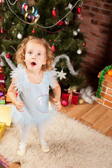 Preaty little girl  smiling near the Christmas tree