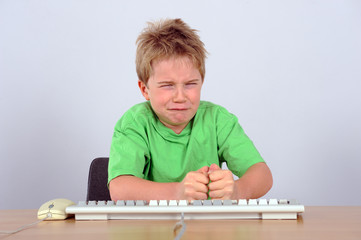 boy is knocking onto the computer- keyboard