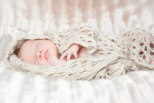 Picture of a newborn baby curled up sleeping on a blanket