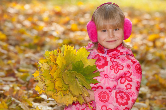 Cheerful little girl with yellow leaves
