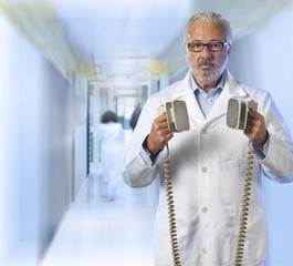 Doctor using a defibrillator - obrazy, fototapety, plakaty