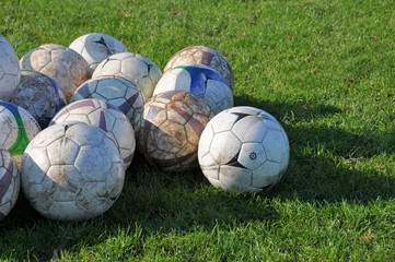 Fototapeta na wymiar Bunch of intensively used footballs on grass