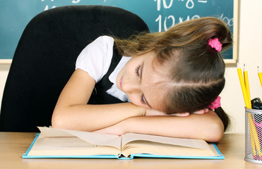 little schoolgirl sleep in classroom near blackboard