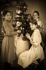 Vintage photo of  daughters with mother decorating Christmas tre