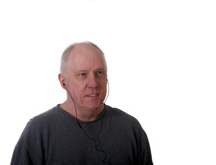 Obraz premium Older Balding Man in Gray Shirt Smiling Listening to Earbuds